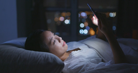 Woman use of mobile phone and lying on bed at night