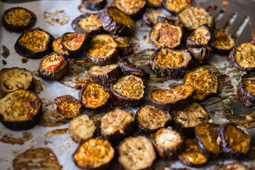 Roasted, grilled eggplants round slices with oregano herbs, spices baked on parchment paper in oven. Vegan vegetarian healthy lunch or dietary dinner.