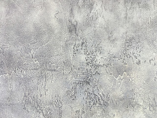 Old gray wall covered with uneven plaster. Texture of vintage shabby silver stone surface, closeup.