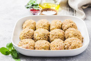 Healthy oven baked chicken rissoles on baking dish, ready for cooking. Selective focus, space for text.