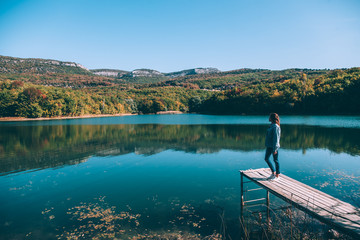 Fototapeta premium Person sitting on peer by the lake