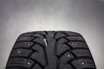 Close up of winter tire with a nail in Finland. Focal point is the nail in the middle of the image. Image includes a white smoke effect.