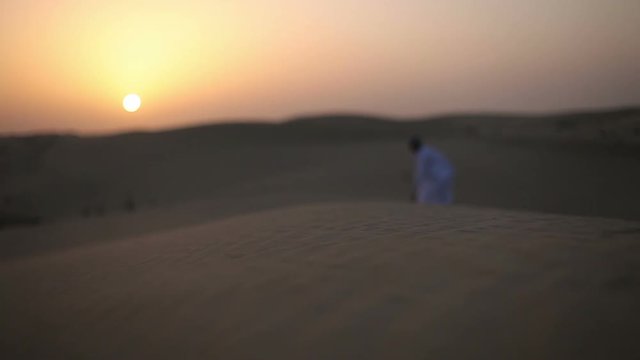Weary wayfarer goes in the desert at sunset