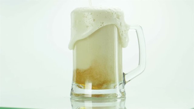 cold mug of beer with foam isolated on white background foam is spinning around its axis slow motion