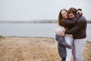 Family with a son having fun at the lake bank in autumn