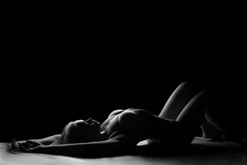 Foto op Plexiglas silhouet van een vrouw liggend op de vloer in haar ondergoed zwart-wit foto © Екатерина Переславце