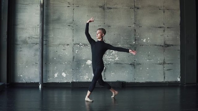 portrait of a male ballet dancer dancing classical ballet in the studio on a dark background. slow motion