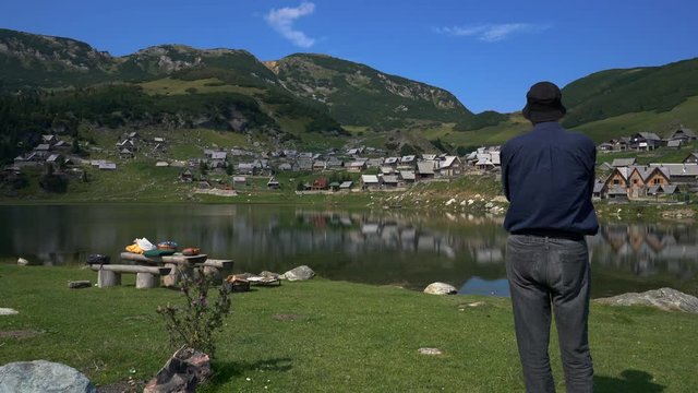 Man looking at the lake and village - (4K)
