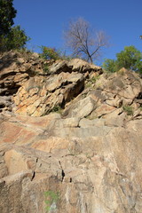 Fototapeta na wymiar Granite rocks in the sun. Texture of granite stone. Background of natural material. Rocky rocks of ancient times. Minimalism