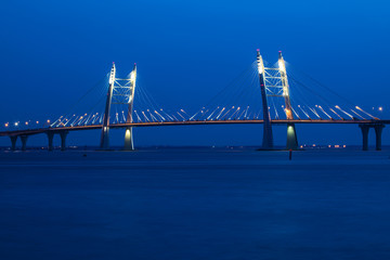 The bridge of circle highway road over Neva river near the mouth of it in the blue hour after the sunset. Night view from Petersburg city to the Finish gulf