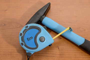Tools, blue measuring tabe and a hammer on a wood table