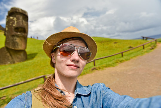 Tourist young  woman doing selfie photo  near Moai statues in the Rano Raraku Volcano in Easter Island, Chile