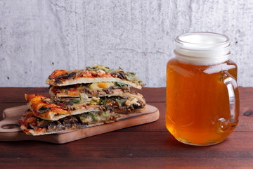 Beer and pizza. Pizza slices on a wooden board. Glass of light beer with foam on a wooden background. Favorite food set for men