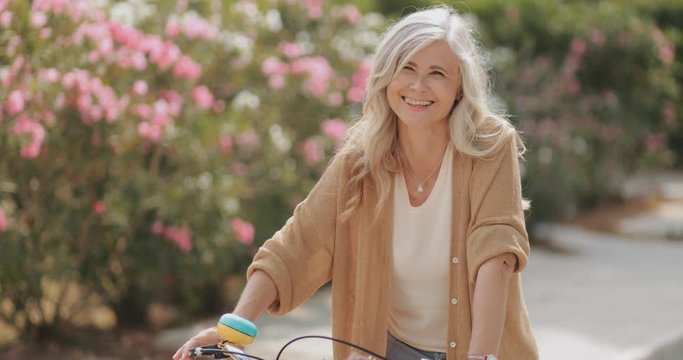 Senior woman riding bike and relaxing in park in spring