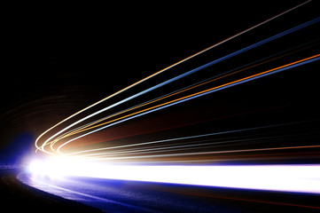 Interesting and abstract light trails in orange, blue and white in a dark car tunnel. Art image that can be used as background or texture - obrazy, fototapety, plakaty