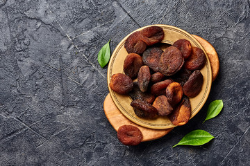 Brown sun dried apricots on black table. Top view.