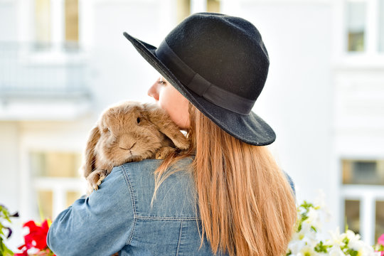Young woman hugs big cute rabbit friend pet in her hands