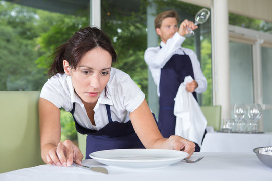 Waitress putting tableware in exact positions