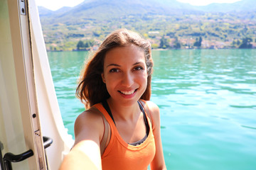 Selfie photo of young model woman on travel cruise vacation in orange tank top enjoying the evening on getaway holidays. Happy traveler vacations in Italy.  © zigres