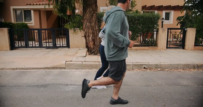 Senior multi-ethnic couple exercising together and jogging on suburban streets