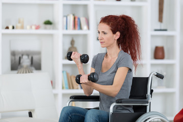 woman sitting in wheelchair working out with dumbbells