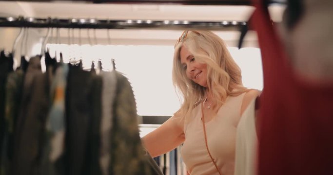 Elegant mature woman shopping for clothes in clothes store