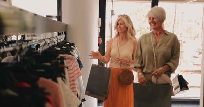 Mature women shopping and entering clothes store in the city