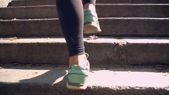 slow motion close up details sport. female legs climbing the steps. sportswoman feet shod in turquoise sneakers