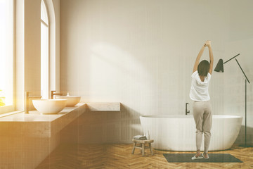 Woman in white bathroom interior, white tub