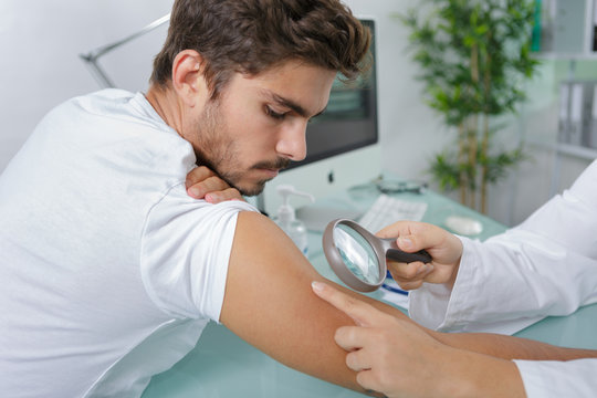 close-up of doctors hands checking mans moles