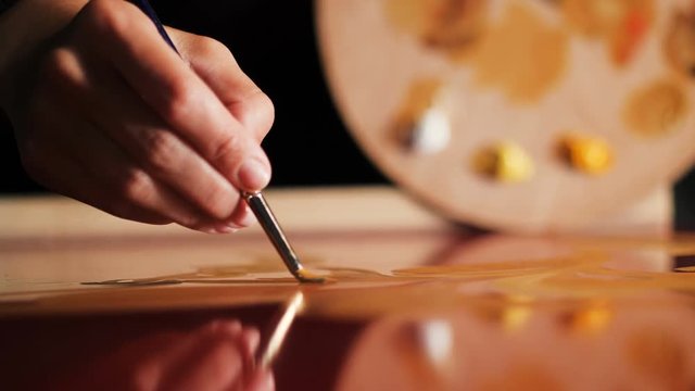 close view artist draws with oil paint on red mirror surface