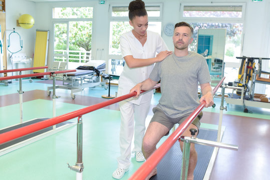 female nurse assisting man in leg exercise