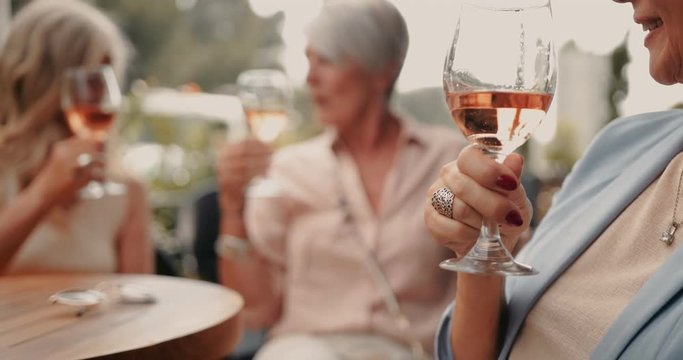 Senior woman holding glass of wine with friends in background