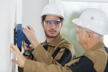 two builders sanding a wall