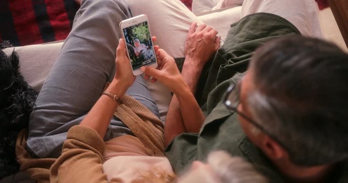 Senior couple at home looking at photographs on smartphone