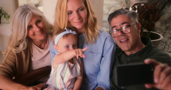 Happy multi-generation family using smartphone and taking selfies at home