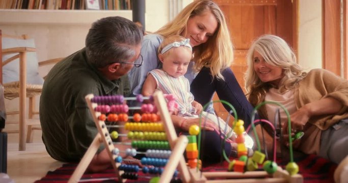 Happy three-generation family playing with little girl on the floor