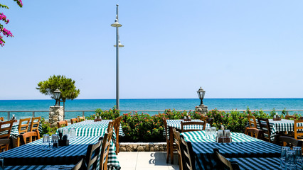 Typical interior of Cyprus restaurant with street flowers and view onto the blue sea