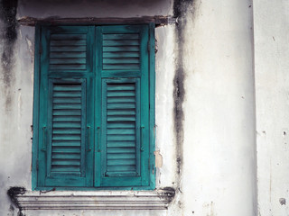 Old green wood window and white wall of building.