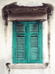 Old green wood window and white wall of building.