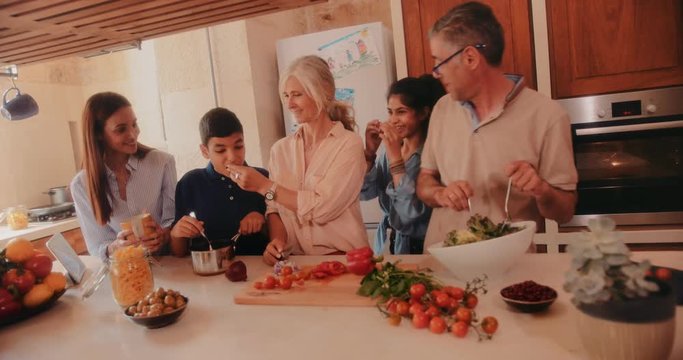 Happy family cooking healthy meal with grandparents in kitchen