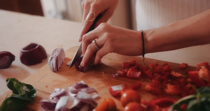 Woman using knife and cutting onion on wooden cutting board