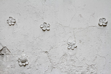 Old white rough wall with gypsum flowers as background or texture