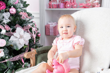 Cute little baby in vintage chair and christmas gifts. Little child having fun near Christmas tree in living room. Loving family Merry Christmas and Happy New Year.