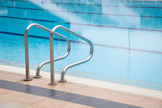 Grab bars ladder in blue the swimming pool.Swimming pool with stair