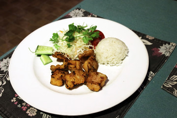 Grilled crocodile meat with steamed rice, cabbage salad and sliced vegetables served in the Vietnamese restaurant