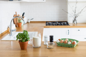 Baking ingredients placed on wooden table, pizza dough. Concept of food preparation. White kitchen on background