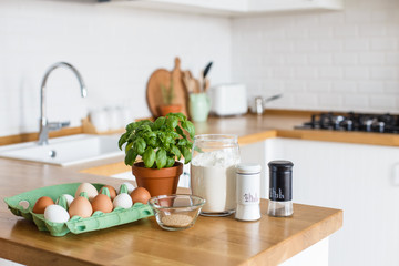 Baking ingredients placed on wooden table, pizza dough. Concept of food preparation. White kitchen on background