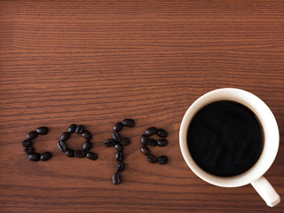 Coffee cup and coffee beans on wooden background. Top view.