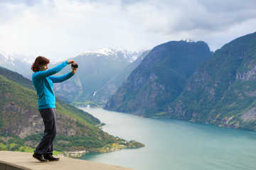 Female tourist taking photo at norwegian fjord